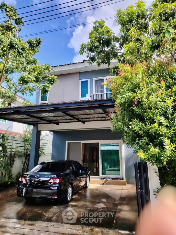 Charming two-story house with carport and lush greenery in a serene neighborhood.