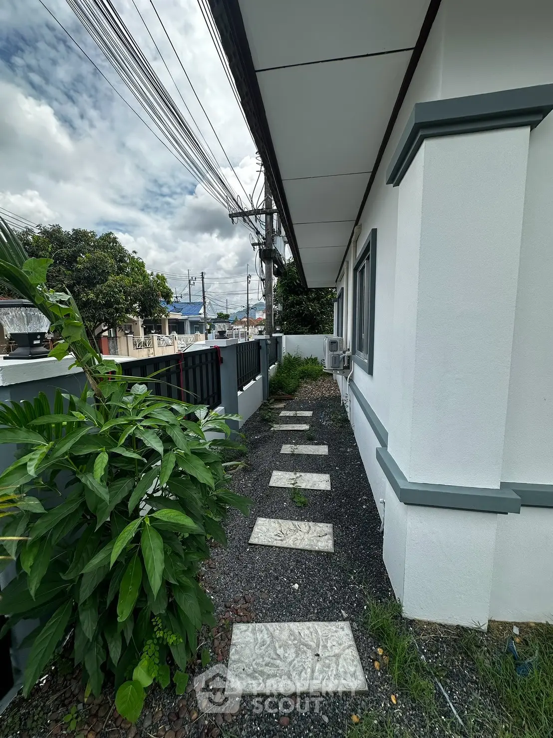 Charming exterior view of a modern house with a landscaped pathway and lush greenery.