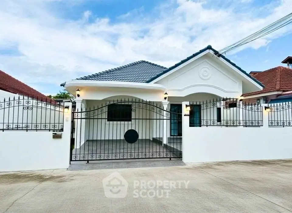 Charming single-story house with gated entrance and tiled roof in a serene neighborhood.