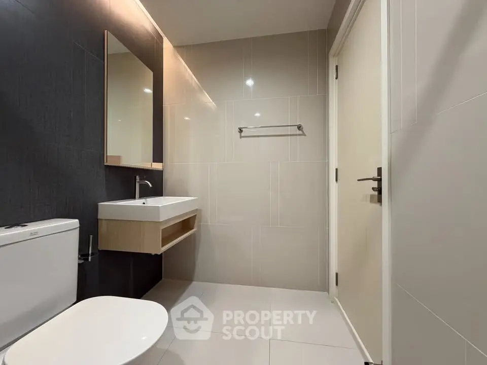 Modern bathroom with sleek design, featuring a wall-mounted sink and contemporary fixtures.