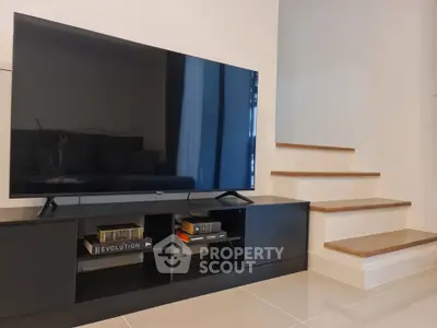 Modern living room with sleek TV setup and stylish staircase