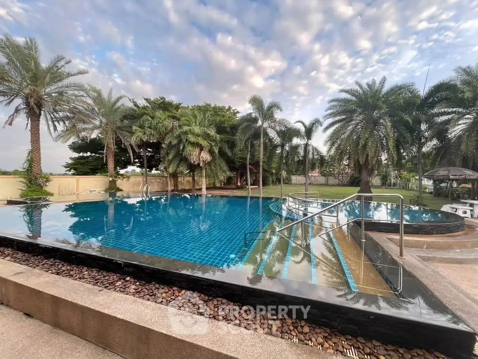 Luxurious infinity pool surrounded by lush palm trees and serene garden setting.