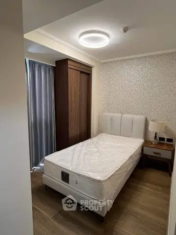 Cozy bedroom with modern lighting and elegant wallpaper, featuring a single bed and wooden furniture.