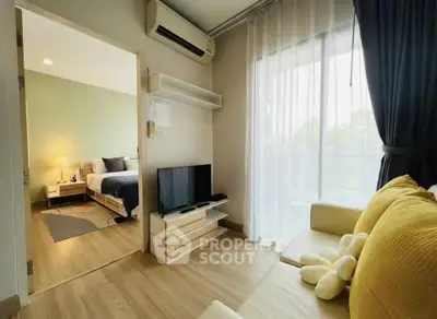Modern living room with cozy sofa, TV, and view into stylish bedroom, featuring elegant decor and natural light.