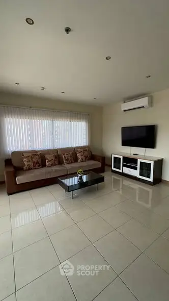 Spacious living room with modern sofa, TV, and air conditioning unit.