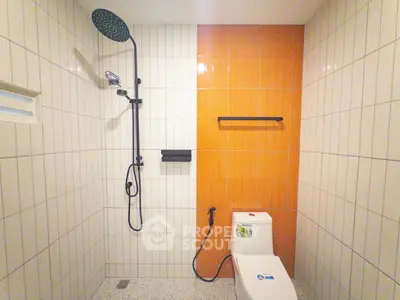 Modern bathroom with stylish shower and vibrant orange accent wall