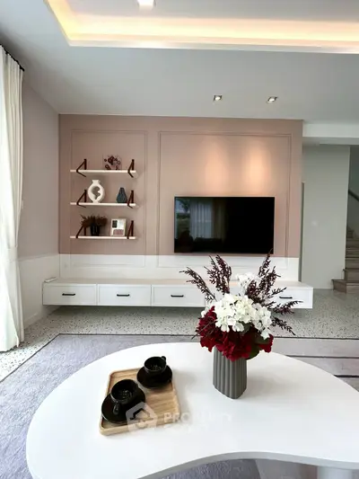 Modern living room with stylish decor and mounted TV, featuring elegant shelving and a chic coffee table.