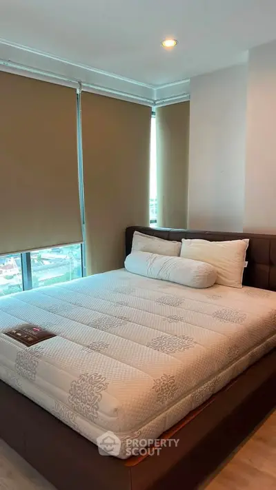 Spacious bedroom with large windows and modern furnishings in a high-rise apartment.