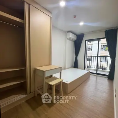 Modern bedroom with wooden flooring, built-in wardrobe, and balcony access in a stylish apartment.