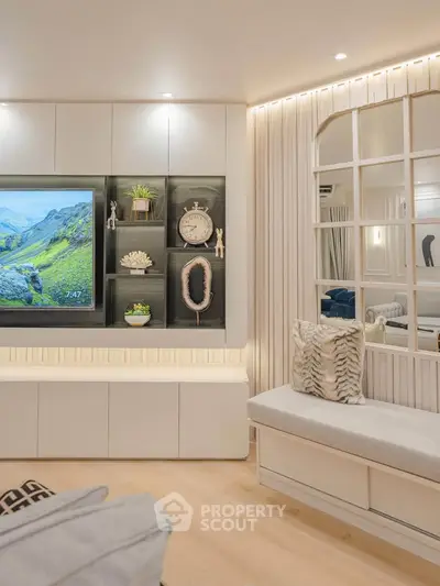 Modern living room with stylish decor and built-in shelving, featuring a cozy seating area and elegant lighting.