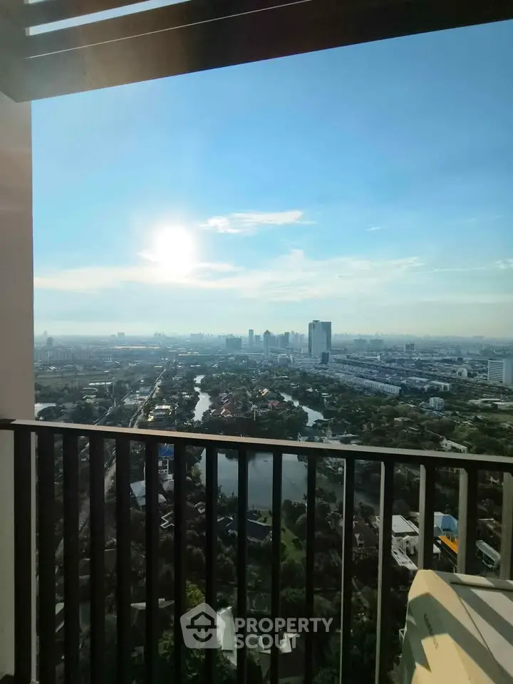 Stunning high-rise balcony view overlooking city skyline and lush greenery, perfect for urban living.
