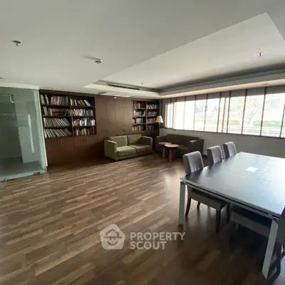 Spacious living room with wooden floors, large windows, and a cozy seating area.