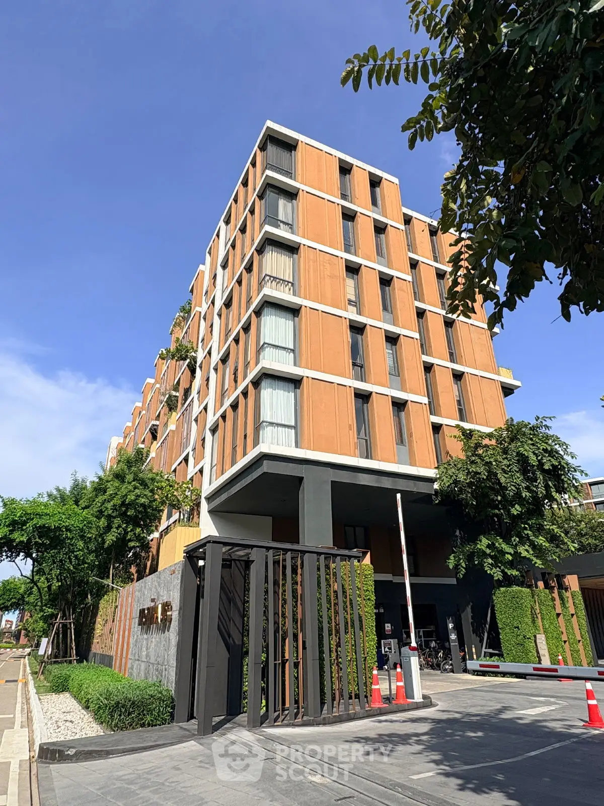 Modern apartment building with lush greenery and secure entrance in urban setting.
