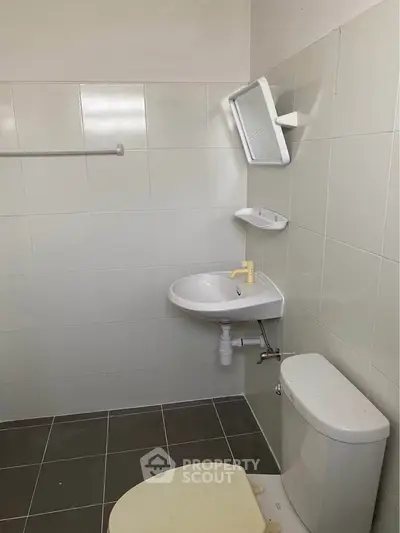 Compact bathroom with wall-mounted sink and toilet, ideal for small spaces.