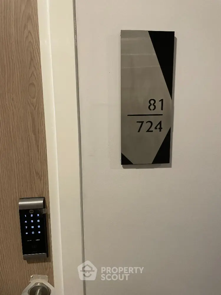 Modern apartment door with electronic lock and stylish room number plaque