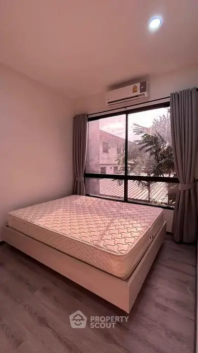 Modern bedroom with large window and air conditioning, featuring a comfortable mattress and stylish curtains.