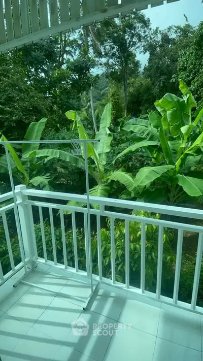 Charming balcony with lush green garden view, perfect for relaxation and enjoying nature.