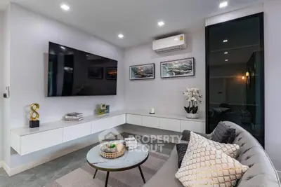 Modern living room with sleek design, featuring a large TV, stylish sofa, and elegant decor.