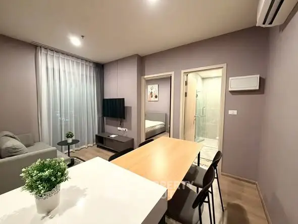Modern living room with dining area and bedroom view in open layout apartment.