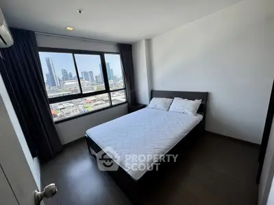Modern bedroom with city view, featuring a comfortable bed and large window in a high-rise apartment.