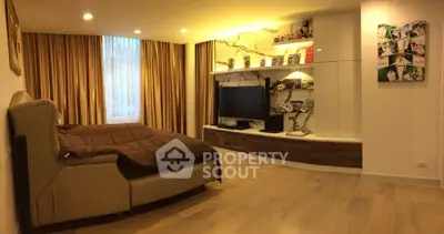Spacious bedroom with modern decor and entertainment center, featuring elegant lighting and wooden flooring.