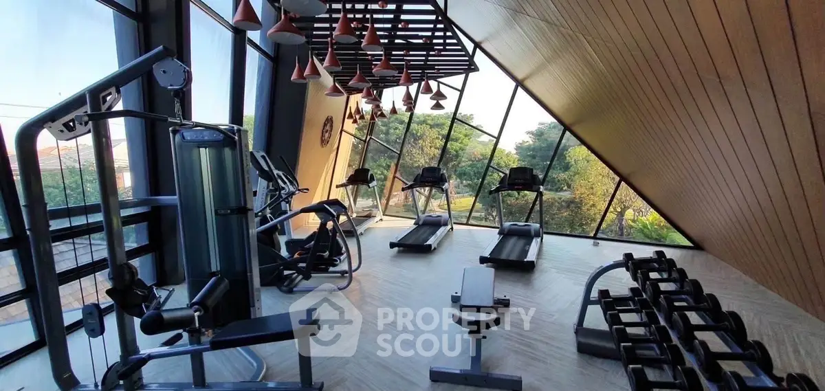 Modern gym with large windows and state-of-the-art equipment in a luxury building.