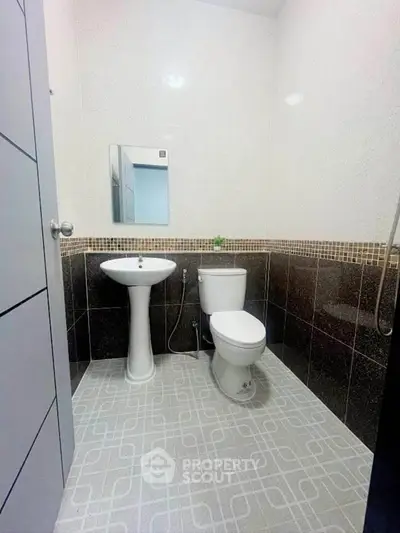 Modern bathroom with pedestal sink and toilet, featuring stylish tile design.