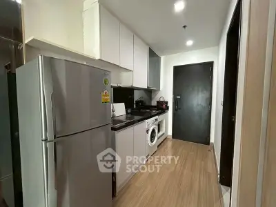 Modern kitchen with sleek appliances and wooden flooring in a stylish apartment.