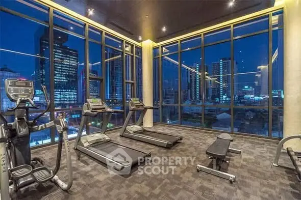 Luxury gym with city view in high-rise building, featuring modern equipment and floor-to-ceiling windows.