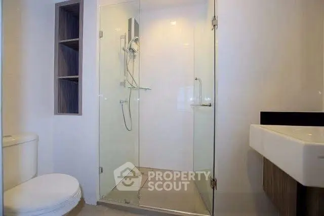 Modern bathroom with glass shower enclosure and sleek fixtures.
