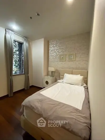 Cozy bedroom with elegant decor and natural light from window, perfect for relaxation.