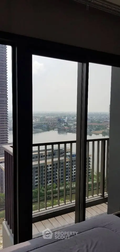 Stunning high-rise apartment view with balcony overlooking cityscape and river.