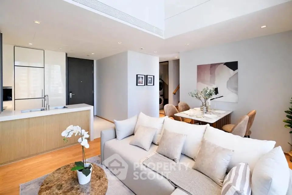 Luxurious open-plan living room with modern kitchen and elegant dining area, featuring stylish decor and natural light.