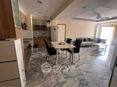 Spacious open-plan kitchen and living room with modern furnishings and marble flooring.