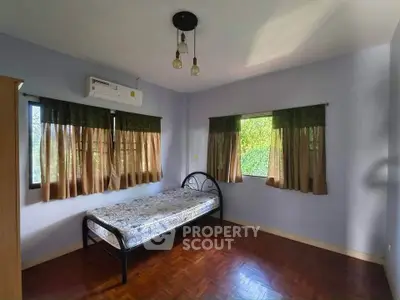 Spacious bedroom with natural light and wooden flooring