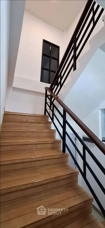 Modern staircase with wooden steps and sleek railing in a contemporary home.