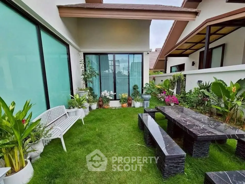 Charming garden area with modern outdoor furniture and lush greenery in a stylish residential setting.