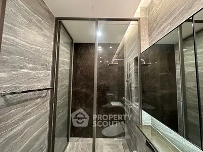 Luxurious modern bathroom with sleek glass shower and elegant stone tiles.