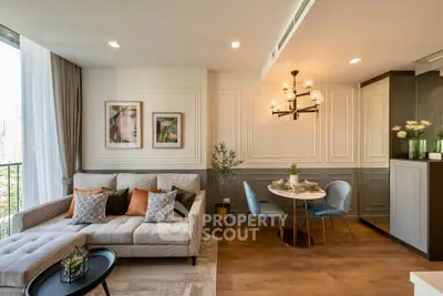 Elegant living room with stylish decor and dining area, featuring a cozy sofa and modern chandelier.