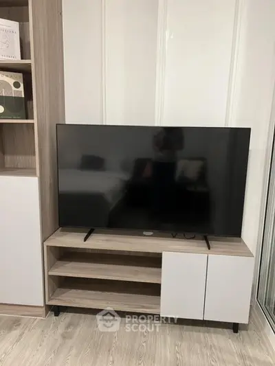 Modern living room with sleek TV stand and large flat-screen TV, featuring stylish built-in shelving and elegant decor.