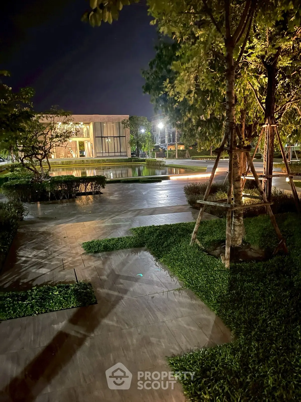 Stunning night view of modern building with lush garden and ambient lighting.