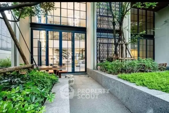 Modern building entrance with lush greenery and large glass windows