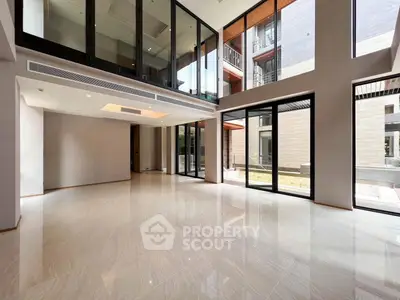 Spacious modern living room with large windows and high ceilings in luxury property.