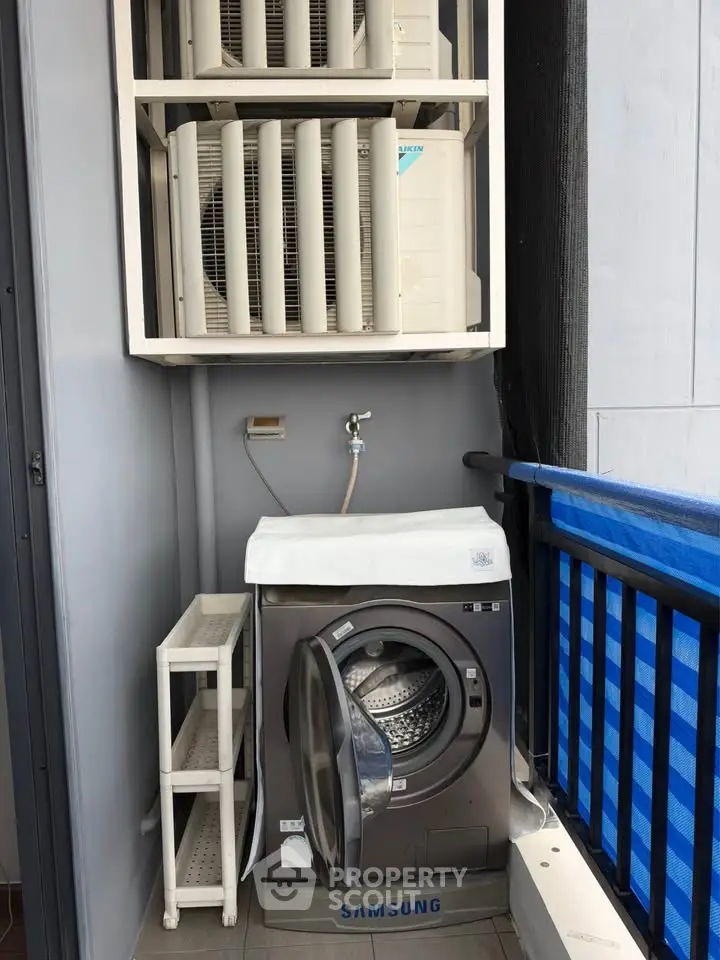 Compact balcony with washing machine and air conditioning units in modern apartment.