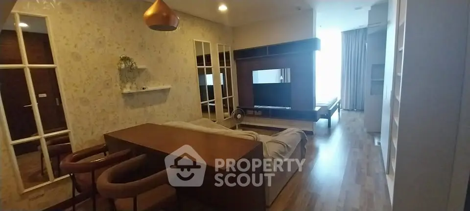 Modern living room with stylish decor and large TV unit, featuring elegant lighting and cozy seating.