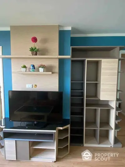 Modern living room with stylish TV unit and shelving, featuring vibrant decor and sleek design.