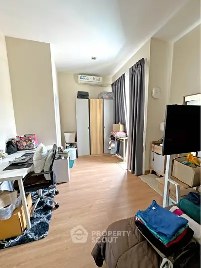 Spacious bedroom with modern decor and ample natural light, featuring a cozy workspace and stylish storage solutions.
