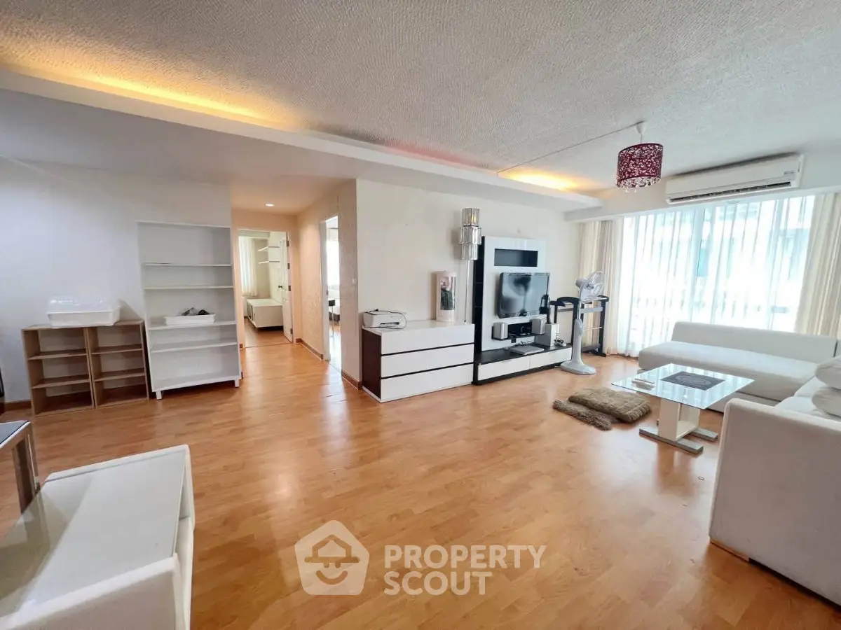 Spacious modern living room with hardwood floors and stylish furniture in a bright apartment.