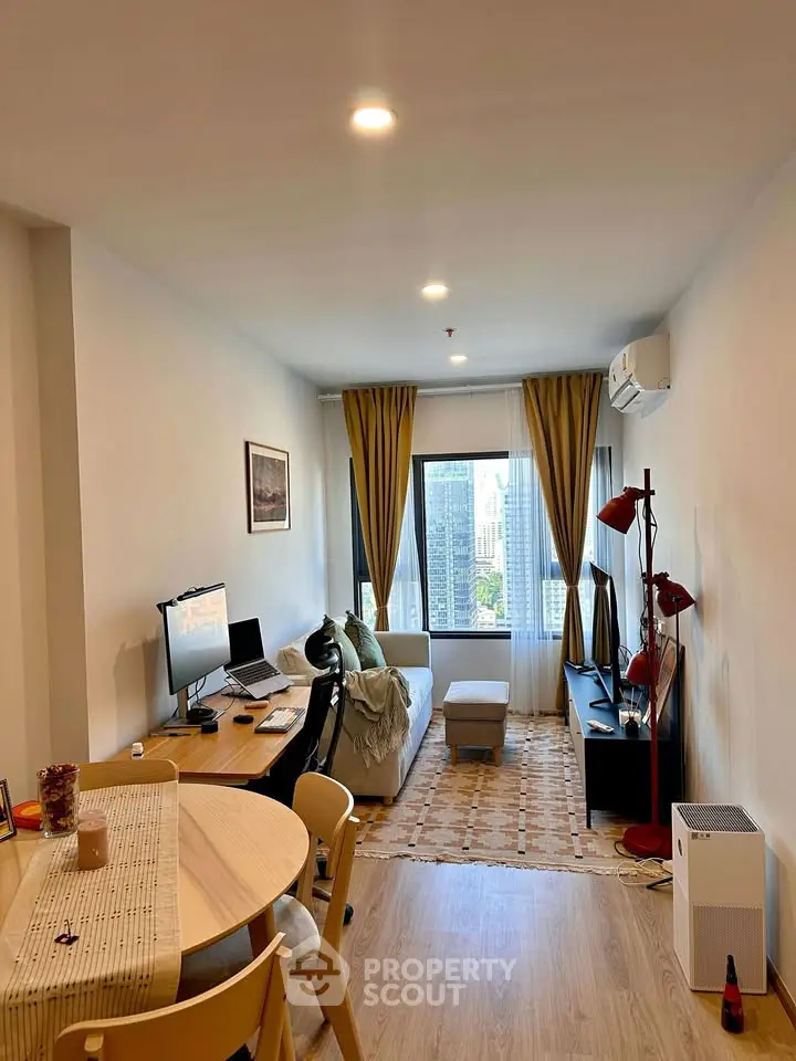 Modern living room with city view, featuring cozy seating and stylish decor in a high-rise apartment.