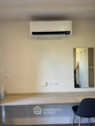Modern study area with sleek desk, mirror, and air conditioning unit in a stylish apartment.